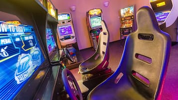 Experience the thrill of racing and hunting in our gaming arcade, featuring a range of machines with steering wheels and display screens.