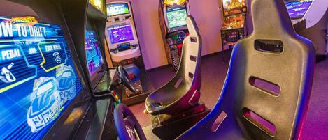 Rivi arcade-tyyppisiä ajopelejä, joissa on ohjauspyörät ja kilpa-istuimet.