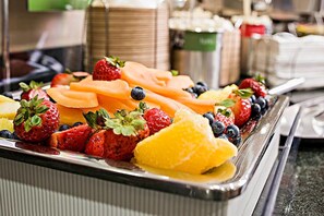 A buffet tray with sliced cantaloupe, strawberries, blueberries, and orange segments.