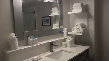 Une salle de bain moderne avec un grand miroir, un lavabo blanc et des porte-serviettes.