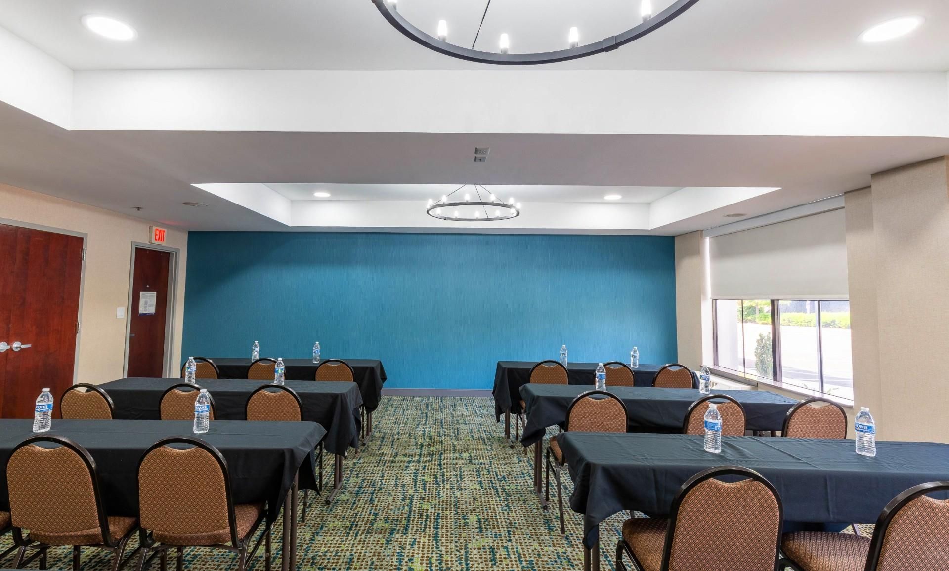 A conference room with tables and chairs, a blue wall, and a patterned carpet.