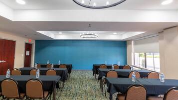A conference room with tables and chairs, a blue wall, and a patterned carpet.