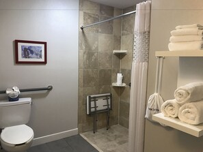 Een badkamer met een douche, toilet en een plank met handdoeken.