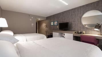 Habitación de hotel con dos camas, un escritorio, un televisor y un espejo.