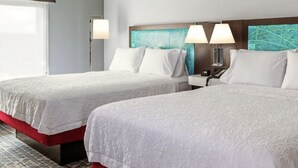 A hotel room with two beds, a nightstand, and a wall with a circuit board design.