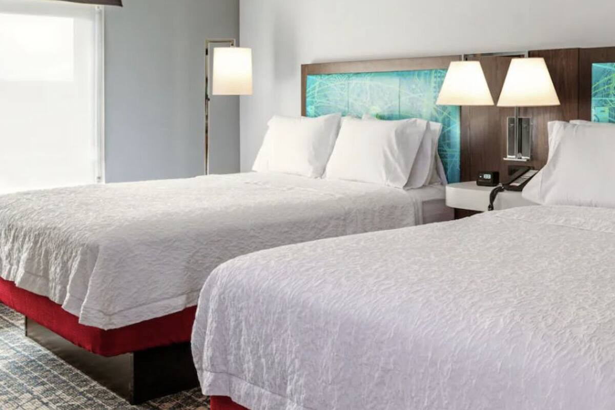 Habitación de hotel con dos camas, una mesita de noche y una pared con diseño de circuito electrónico.