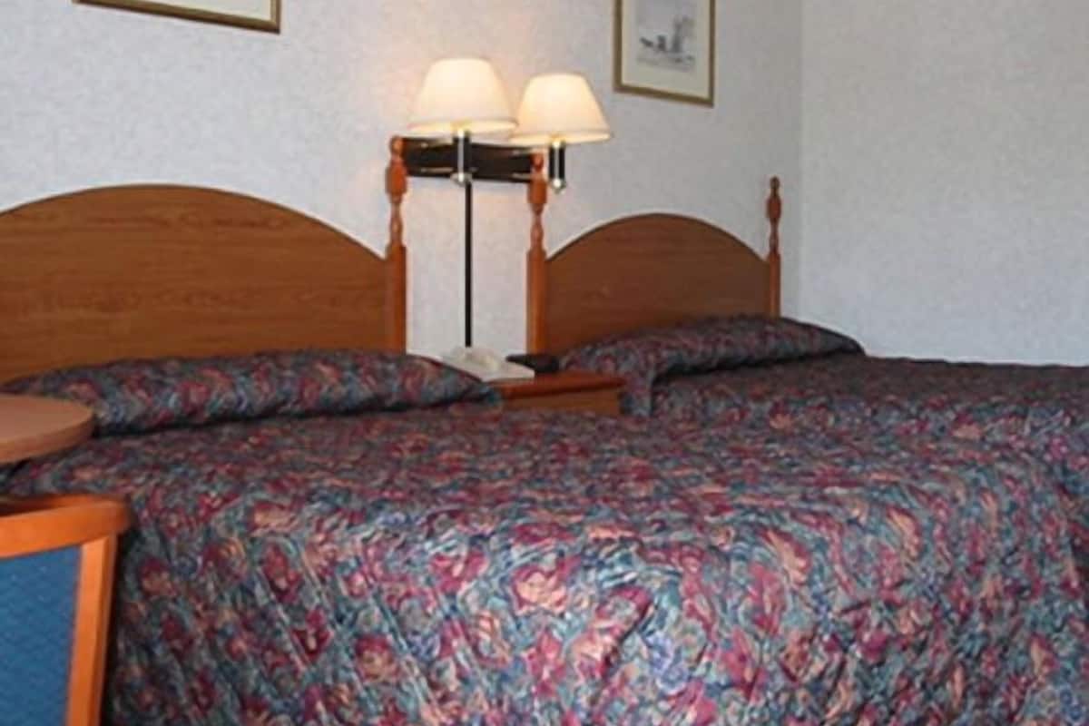 A neatly made bed with a floral bedspread, two bedside lamps, and a framed picture on the wall.
