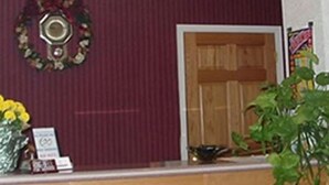 A reception area with a wooden counter, a wreath on the wall, and a potted plant. - Scottish Inn Ronks (Ronks)