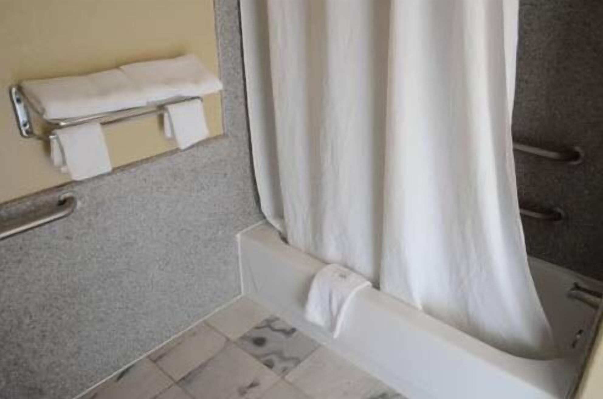 A bathroom with a bathtub, a towel rack, and a shower curtain.