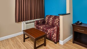 Ein Zimmer mit einem braunen Sofa, einem Holztisch, einer blauen Akzentwand und einem Telefon auf einem Nachttisch.