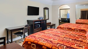 Ein Hotelzimmer mit Bett, Schreibtisch, Stuhl und Fernseher.