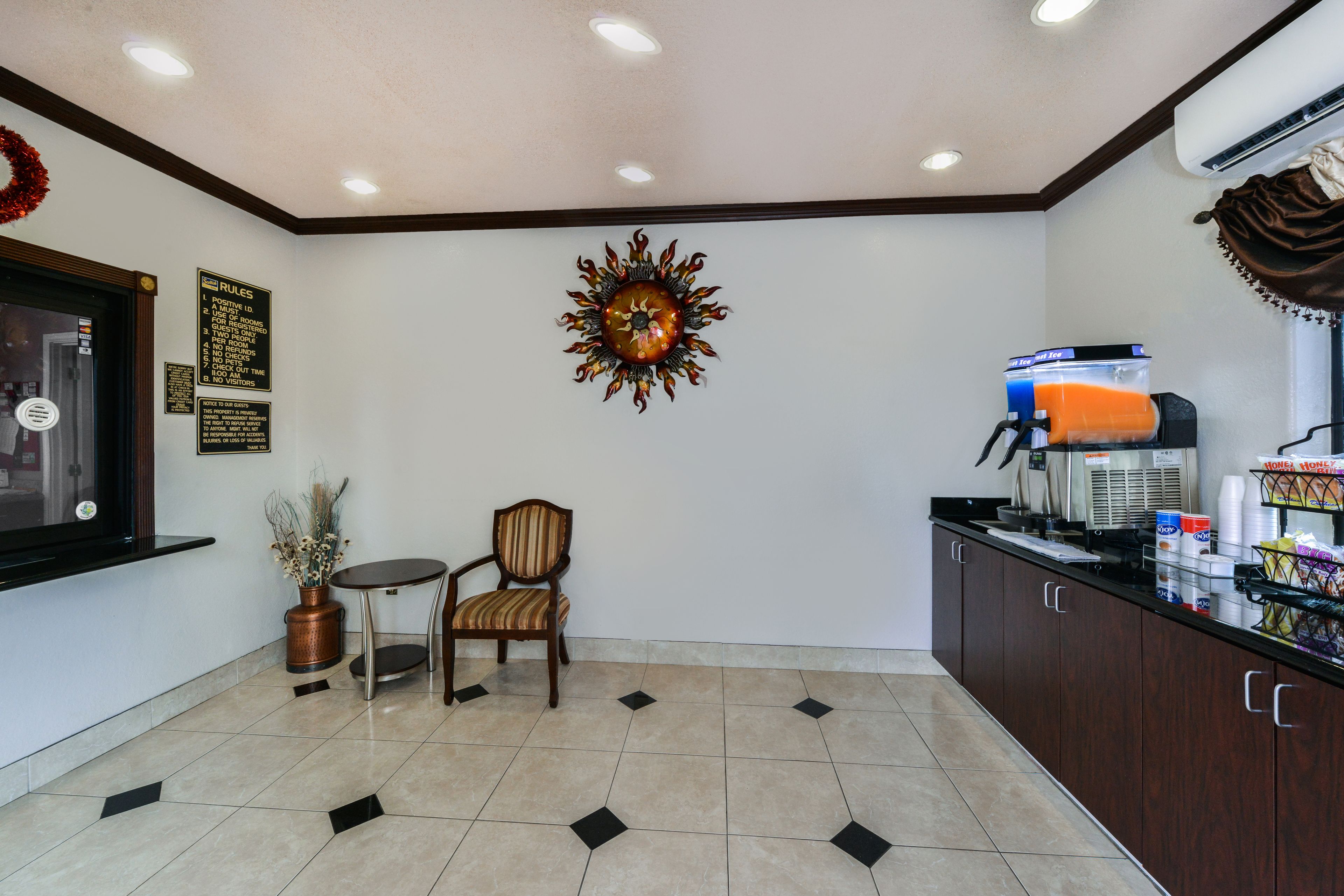 A reception area with a coffee machine, a chair, a small table, and a decorative wall piece.