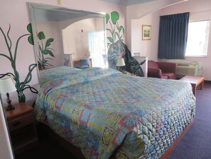 A hotel room with a large bed, a desk, a chair, a lamp, and a window with curtains. - Travelers Inn and Suites Liberty (Liberty)