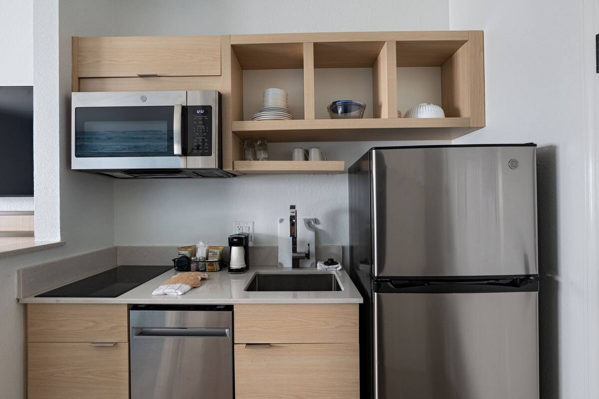 Eine moderne Küche mit eingebauter Mikrowelle, einem Edelstahl-Kühlschrank und Holzschränken.