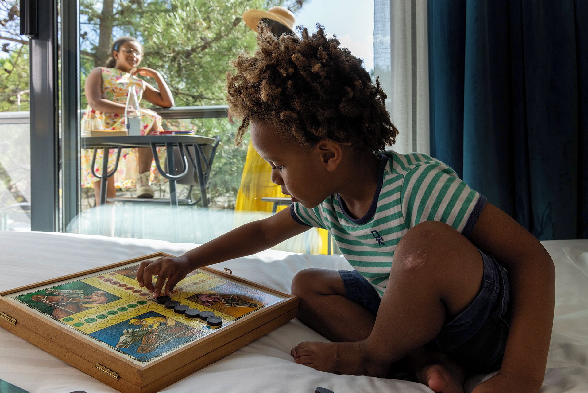 Un enfant joue à un jeu de société en bois sur un lit.