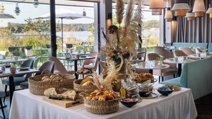 A dining area with tables set for breakfast, featuring bread, pastries, and condiments. - Best Western Plus Hotel Les Rives Du Ter (Larmor-Plage)