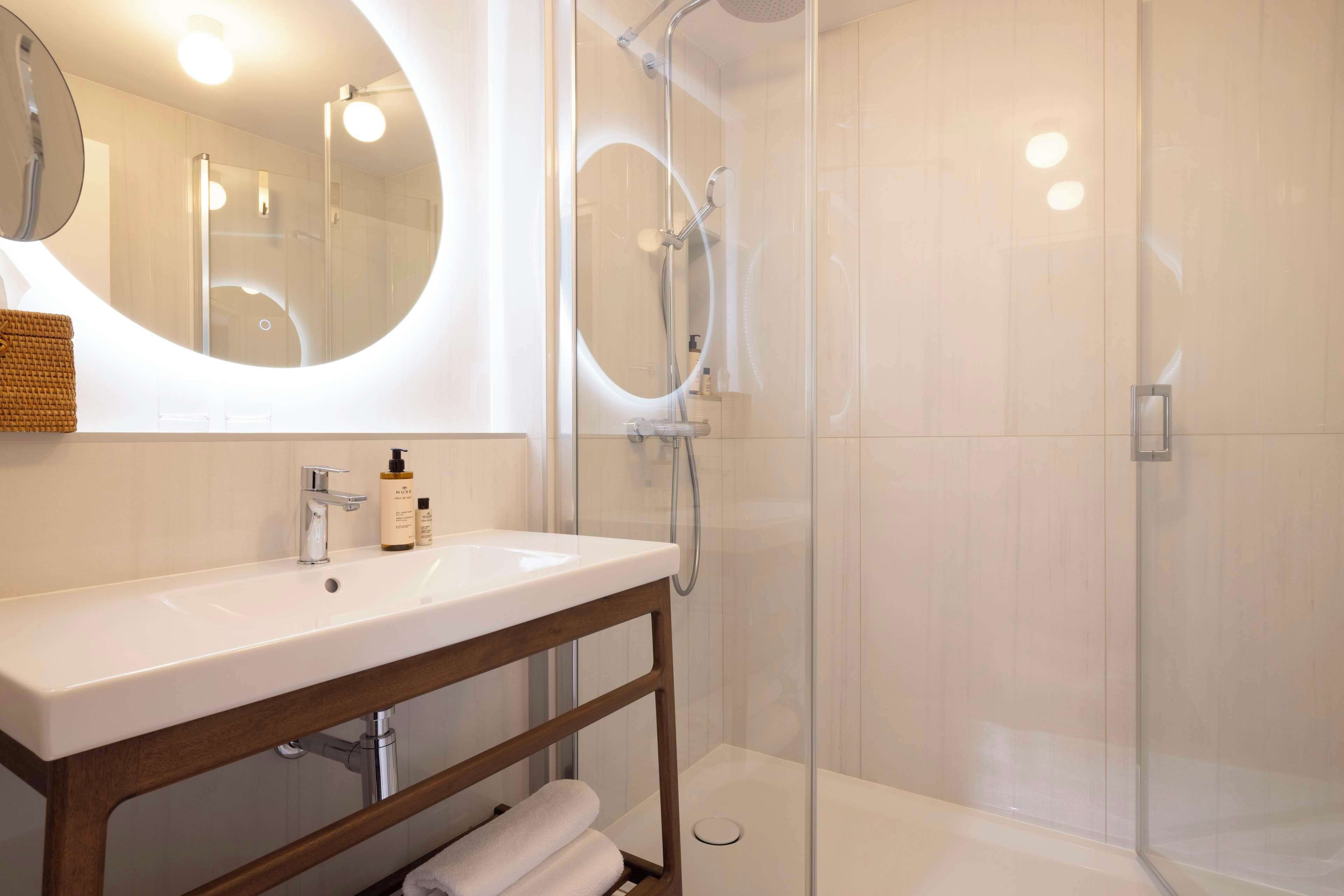 Een moderne badkamer met een wit wastafelmeubel, spiegel en een douchecabine van glas.