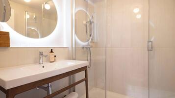 Een moderne badkamer met een wit wastafelmeubel, spiegel en een douchecabine van glas.