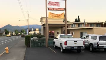 Un motel appelé « Sunset Inn », avec une enseigne au néon, un parking où sont garés plusieurs camions et un poteau d’incendie sur le trottoir.