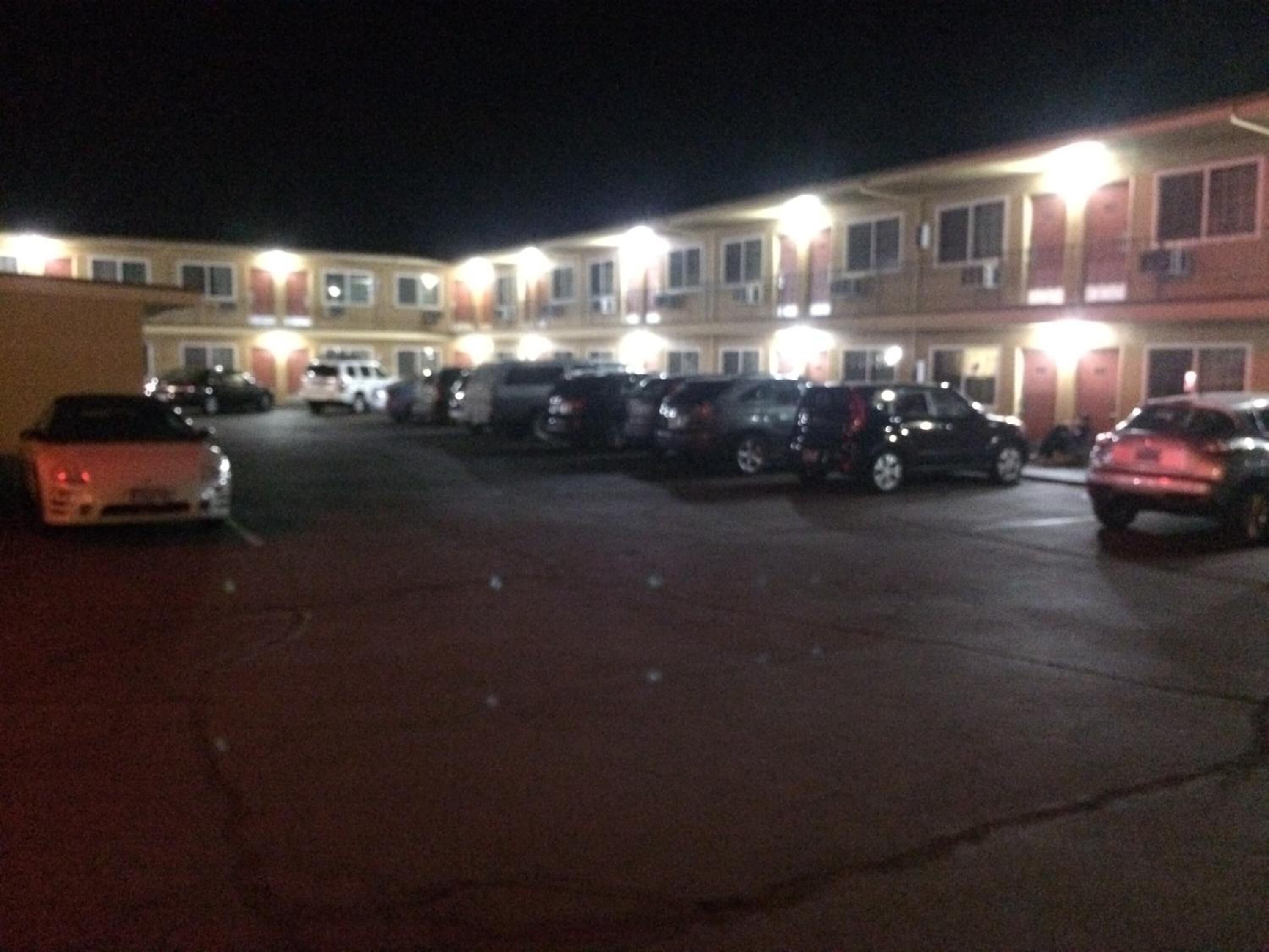 A parking lot with several cars parked in front of a building with multiple windows and balconies.