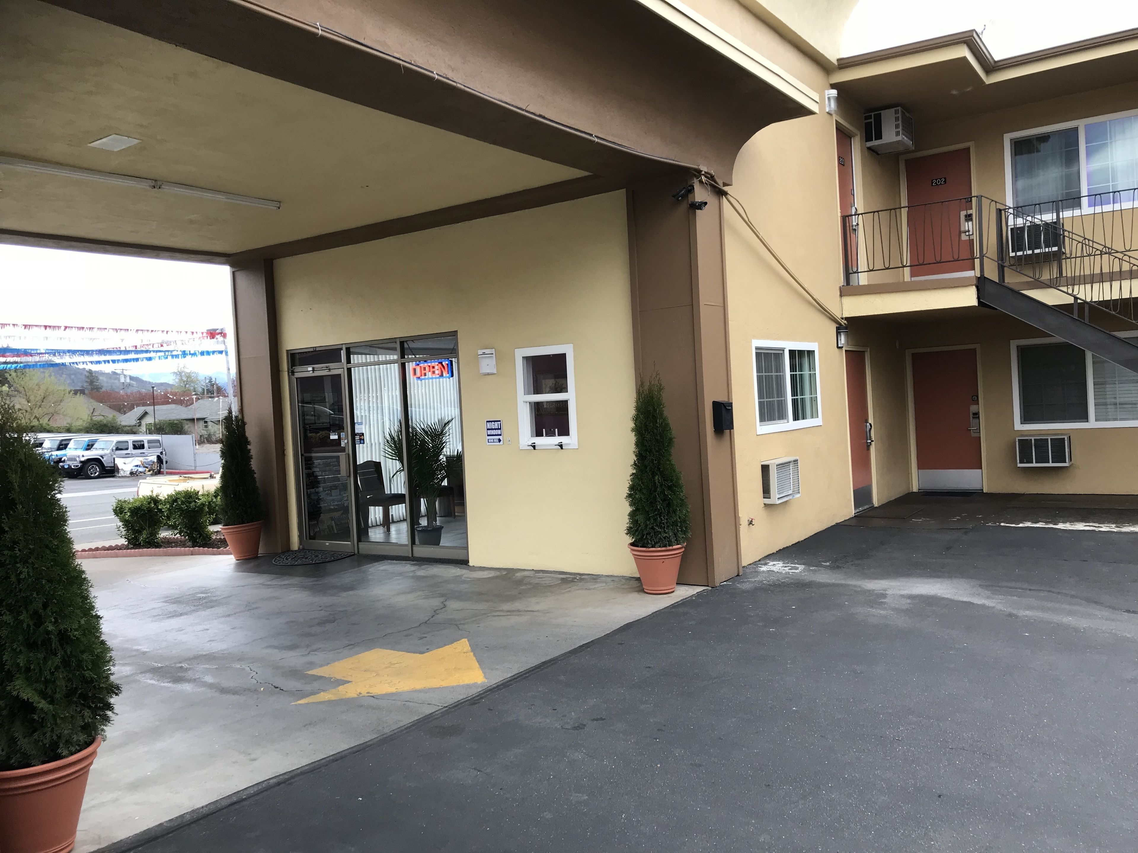 A hotel entrance with a glass door, a parking lot, and a clear view of the street.