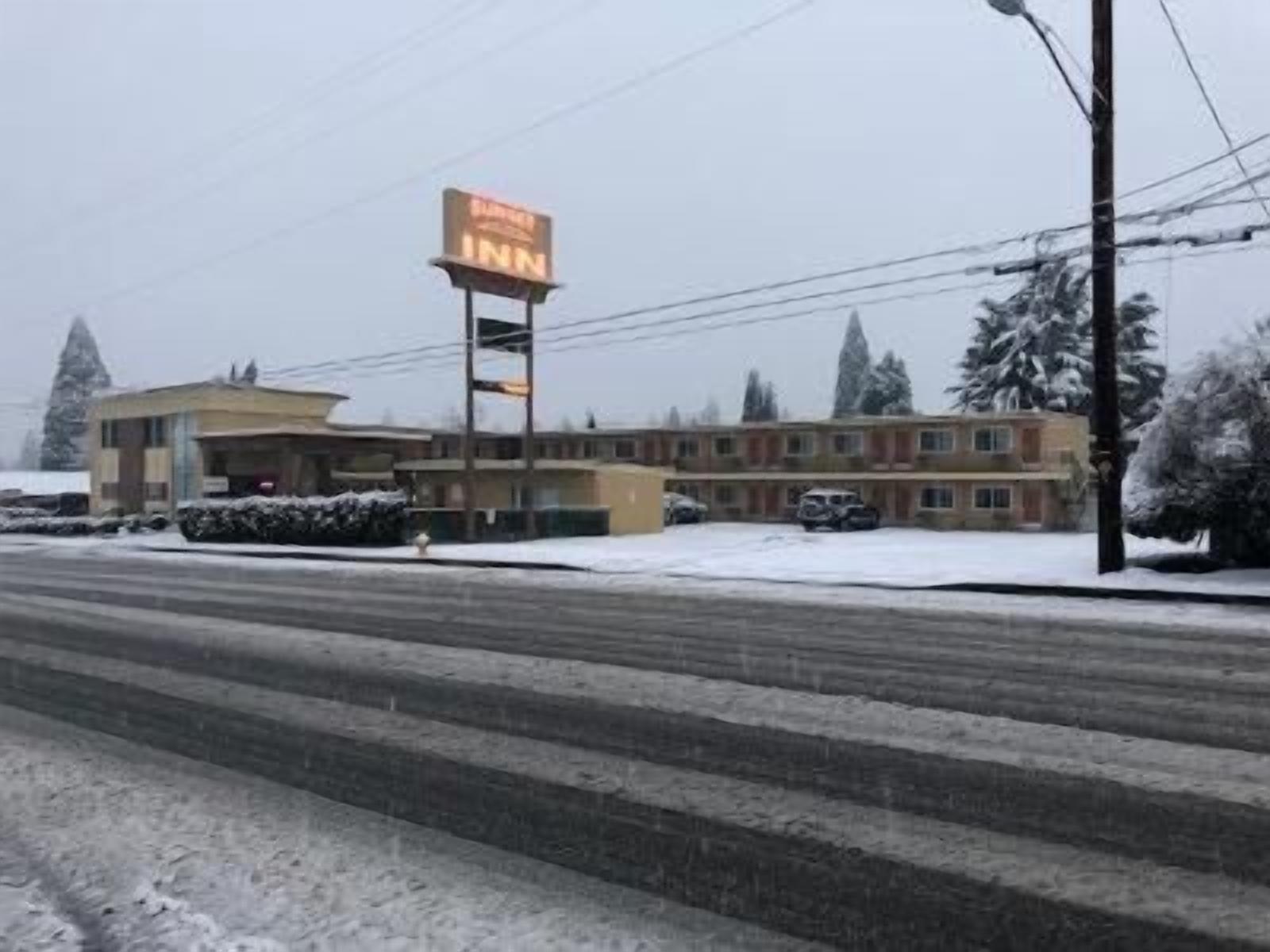 A motel with a prominent 'Inn' sign, a parking lot, and a building with a flat roof and multiple windows.