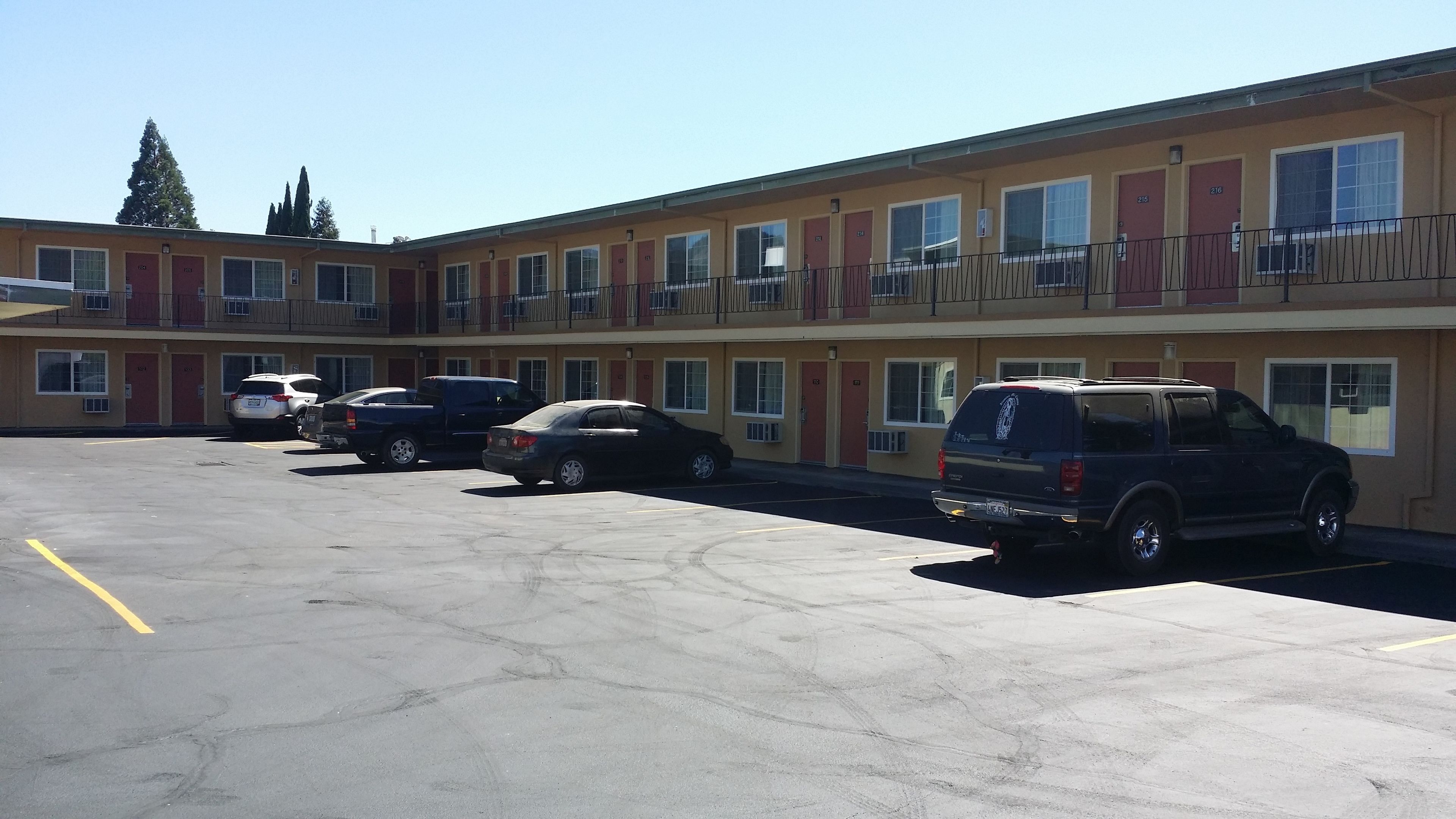 Ein Motel mit mehreren Zimmern, einem Parkplatz und einigen geparkten Autos.
