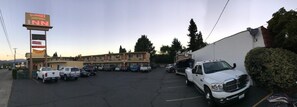 A parking lot with several vehicles, including a white truck, and a motel with multiple floors and a sign for Sunset Inn. - Sunset Inn (Grants Pass)
