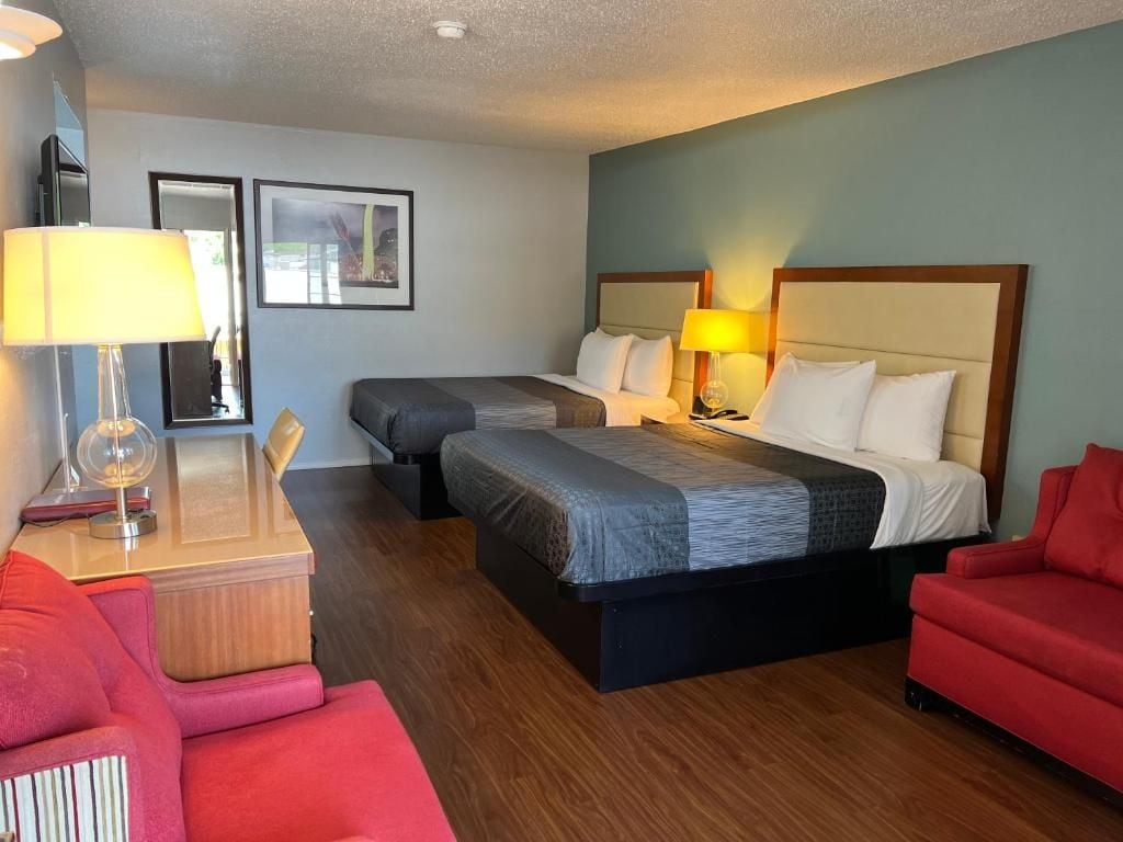 Ein Hotelzimmer mit einem Bett, zwei Nachttischen, einem roten Sessel und einem Holznachttisch.
