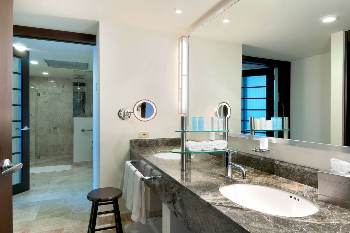A modern bathroom with a large mirror, two sinks, and a glass shower enclosure.
