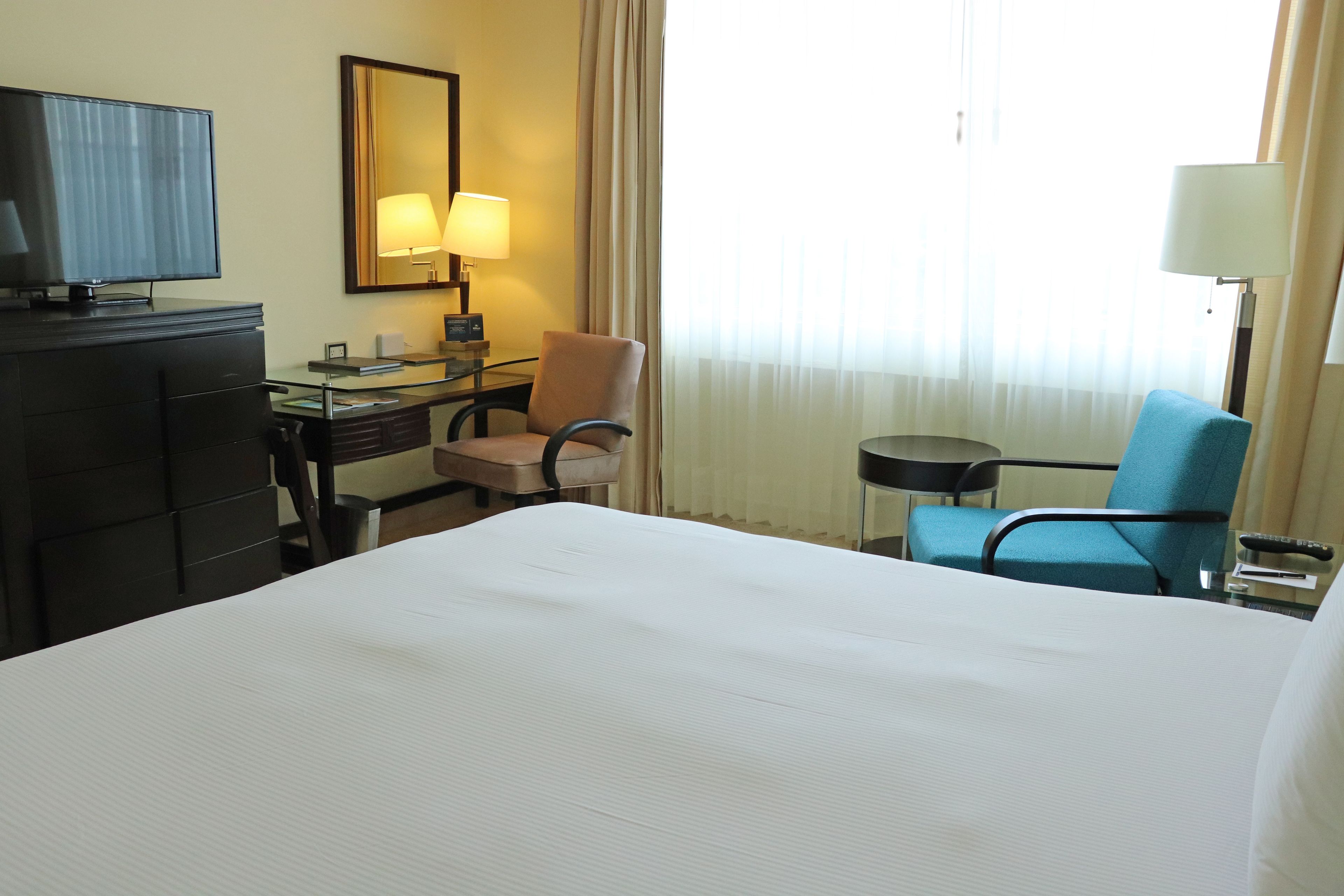 Une chambre d’hôtel avec un grand lit, un bureau avec une lampe, une télévision et une chaise.