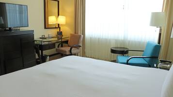 Une chambre d’hôtel avec un grand lit, un bureau avec une lampe, une télévision et une chaise.