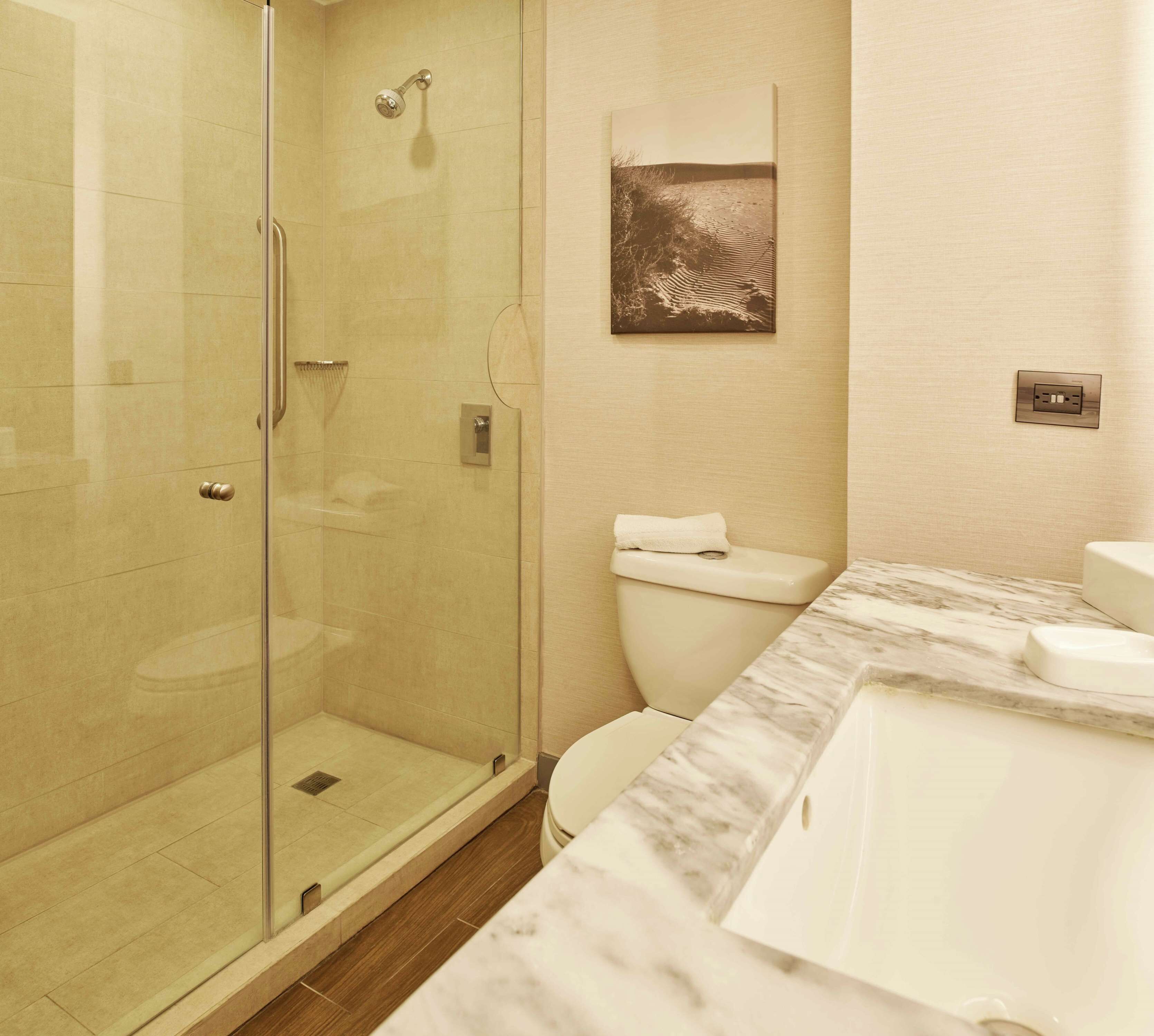 A modern bathroom with a glass-enclosed shower, a marble countertop, and a toilet.