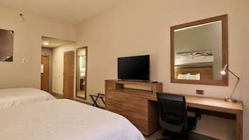 A hotel room with two beds, a desk with a computer, a television, and a large mirror.