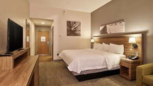 Une chambre d’hôtel avec un lit, une table de chevet, une lampe et un téléviseur posé sur un meuble.