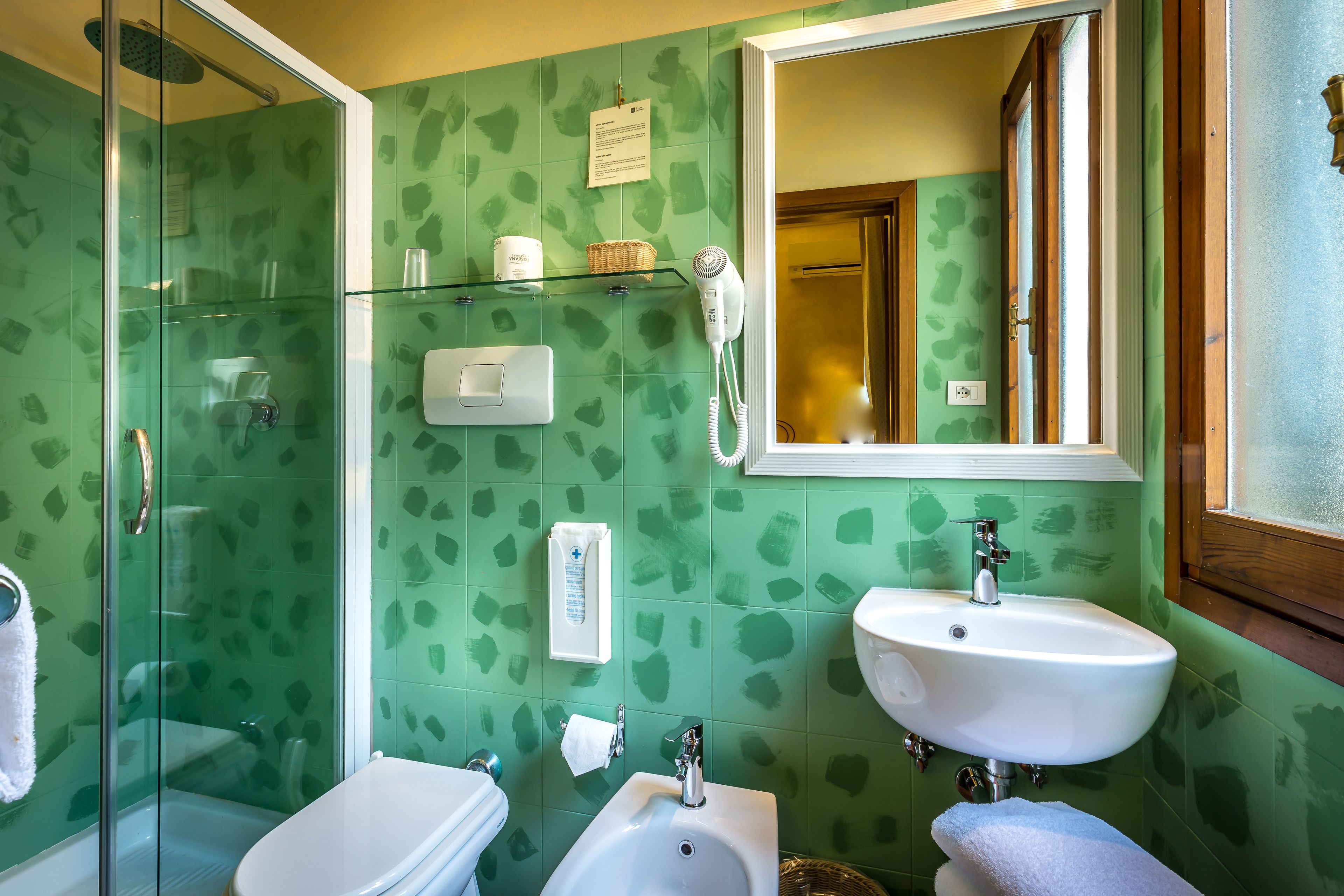 Un baño con cabina de ducha de vidrio, un lavabo blanco y un bidé.