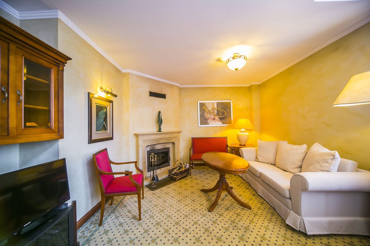 A living room with a fireplace, a sofa, a TV, and a red chair.
