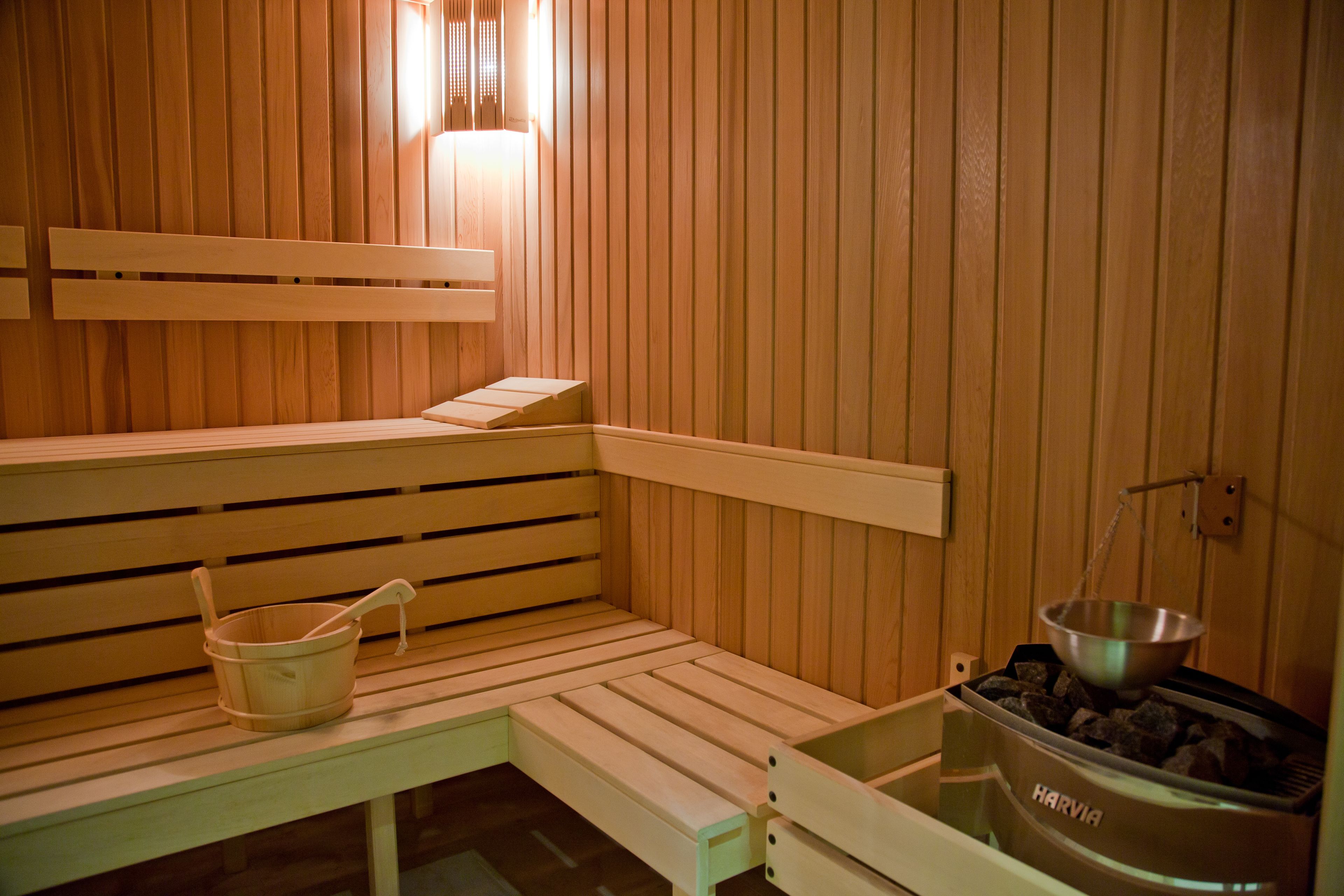 A wooden sauna bench with a bucket and a metal container of stones.