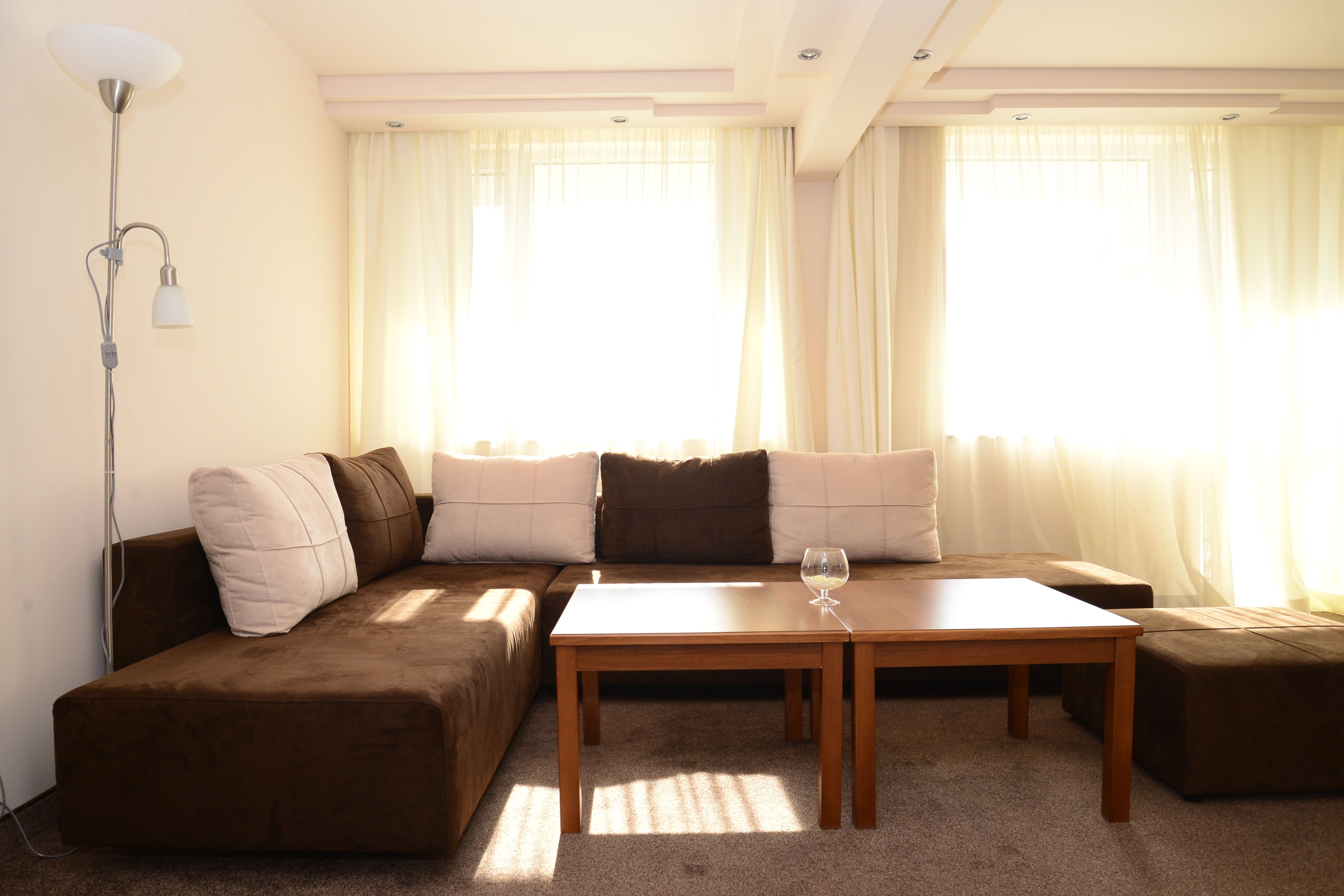Una sala de estar moderna con un sofá seccional marrón, una mesa de centro de madera y una lámpara de pie.