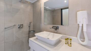 A modern bathroom with a glass-enclosed shower, a white sink, and a handheld showerhead.