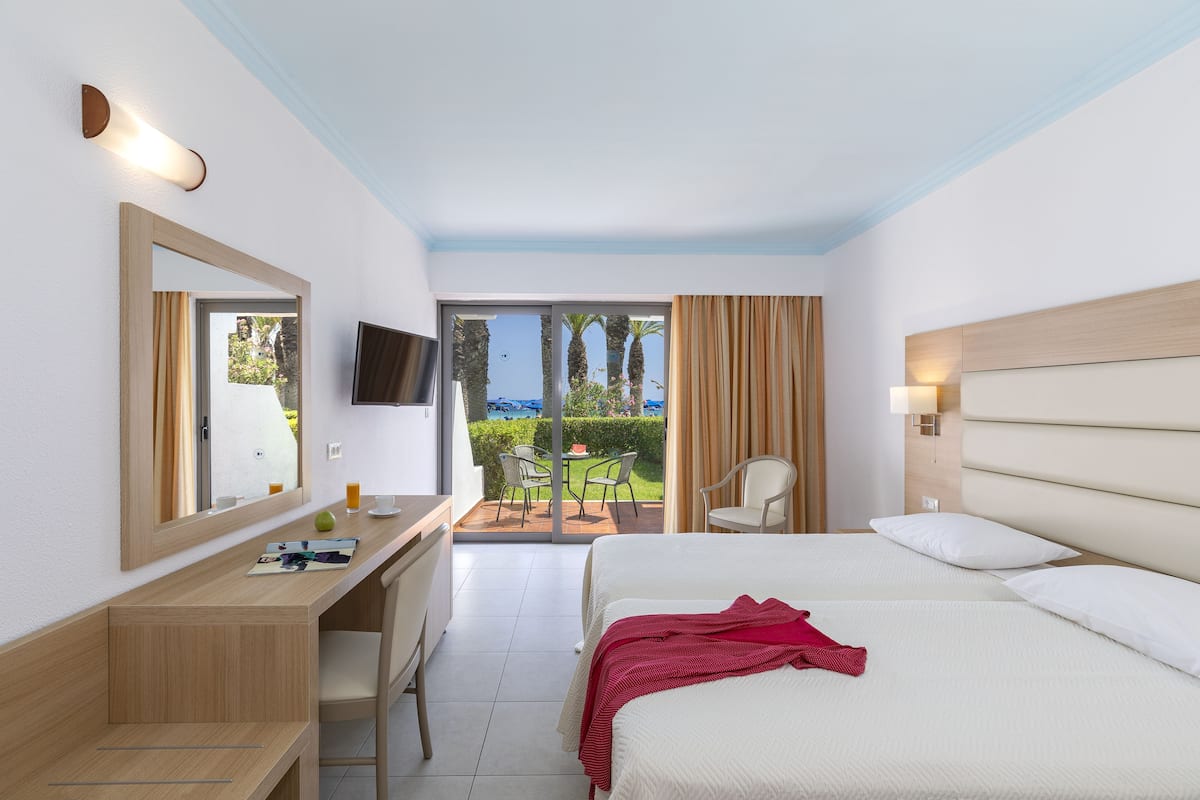 Habitación de hotel con cama, escritorio, silla, televisión y vistas al exterior.