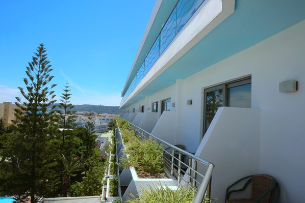 A modern hotel with a balcony, outdoor plants, and a view of the city. - Blue Horizon Hotel (Rhodes)