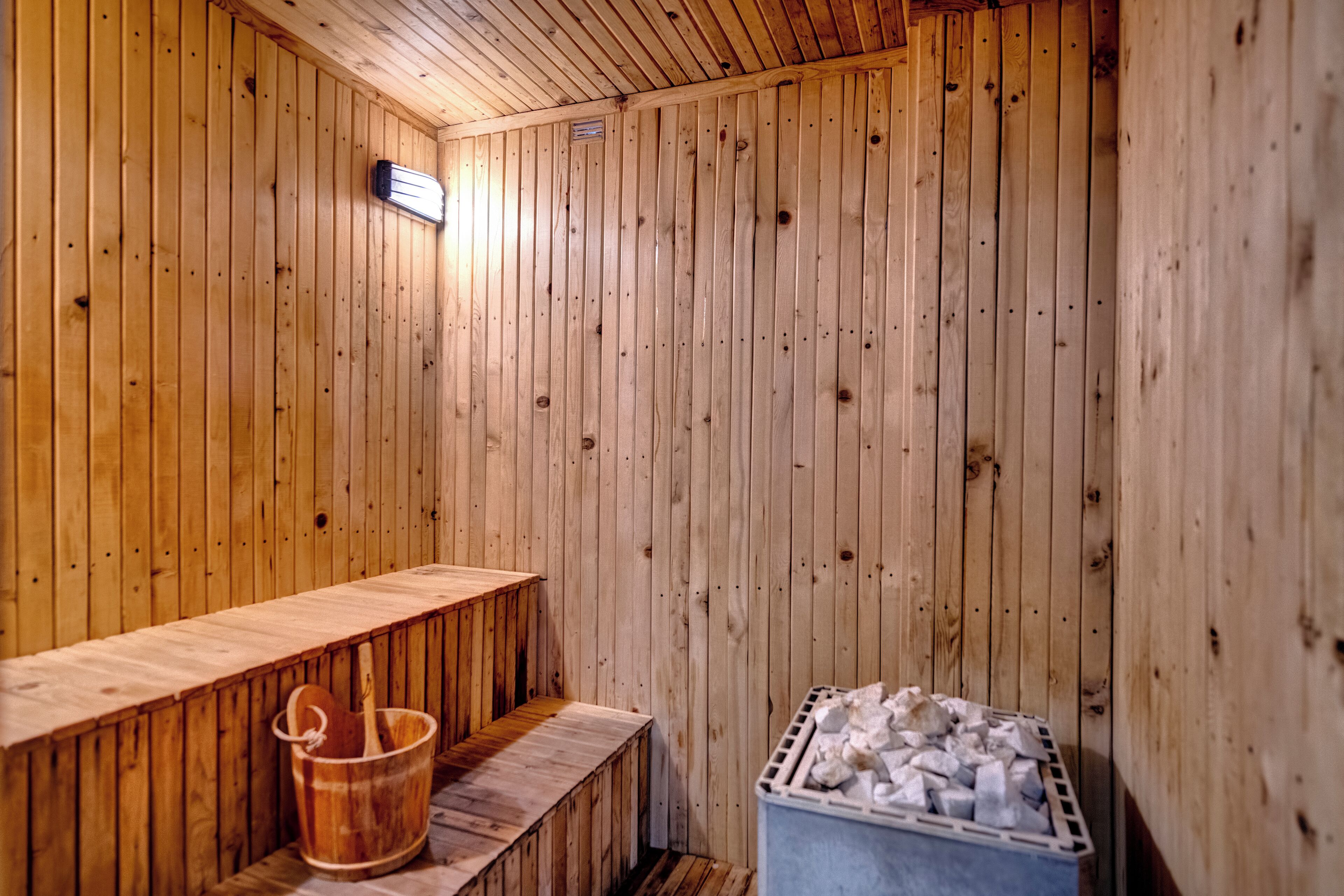 Un sauna avec des murs en bois, un banc, un seau et un récipient rempli de pierres.