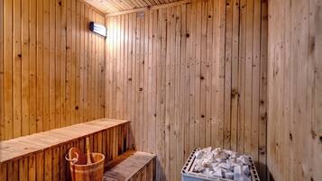 Een sauna met houten wanden, een bank, een emmer en een bak met stenen.