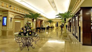 A spacious, well-lit hotel lobby with a polished marble floor, a central floral arrangement, and a piano. - Pearl Continental Rawalpindi (Rawalpindi)