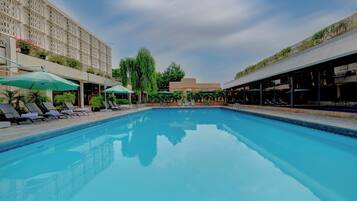 Una piscina al aire libre, sombrillas, tumbonas