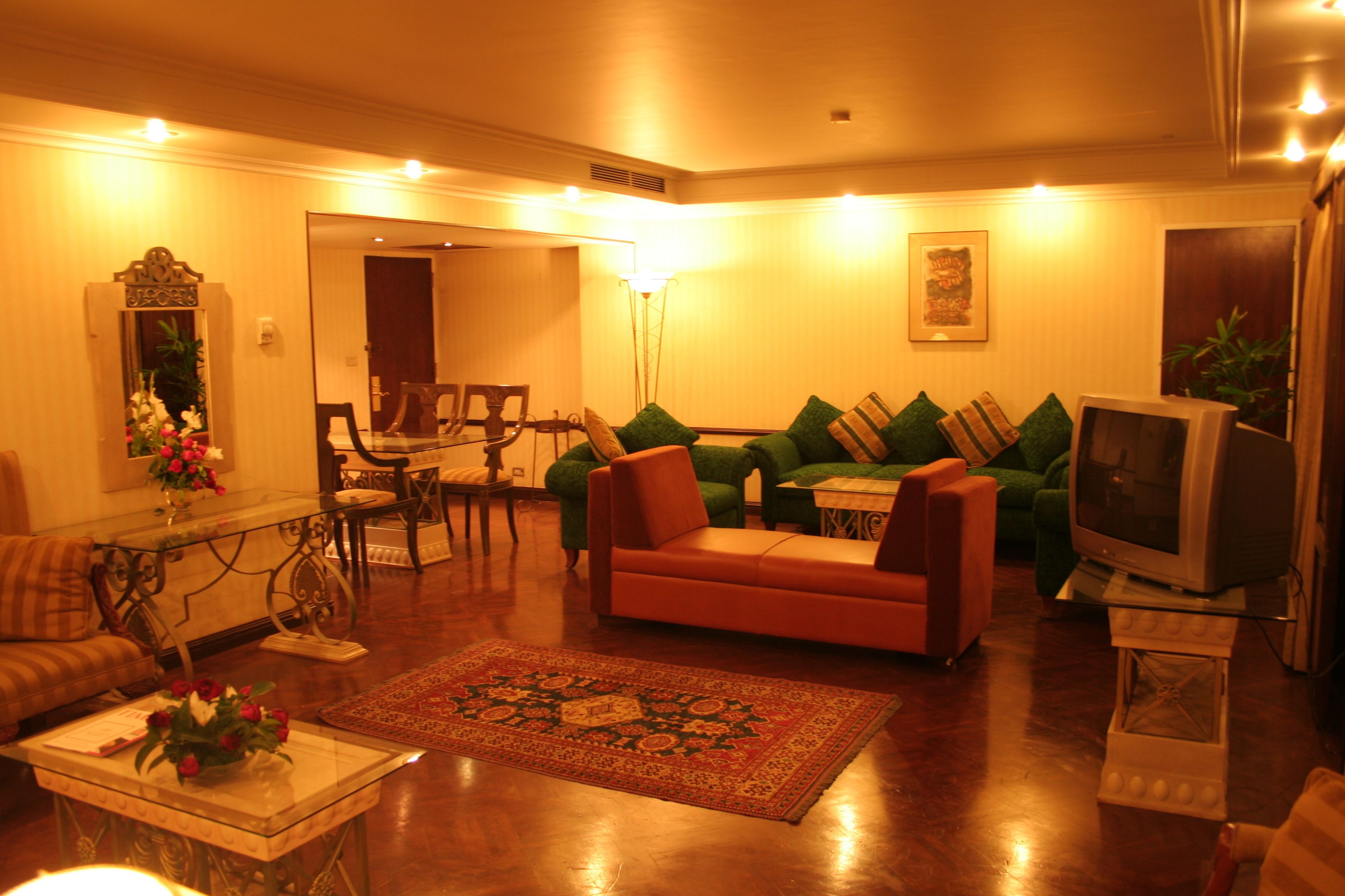 A living room with a sofa, armchairs, a coffee table, a television, and a dining area with chairs and a table.