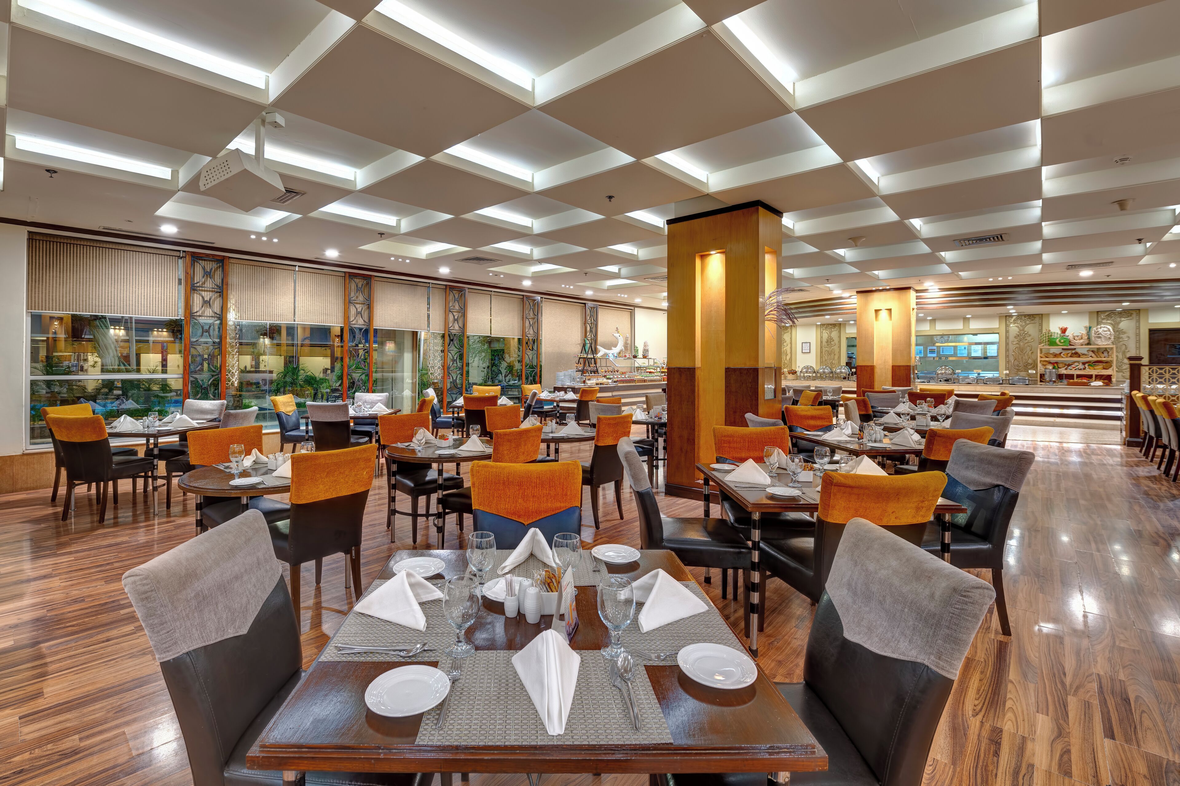 A spacious restaurant with multiple dining tables, chairs, and a modern ceiling design.