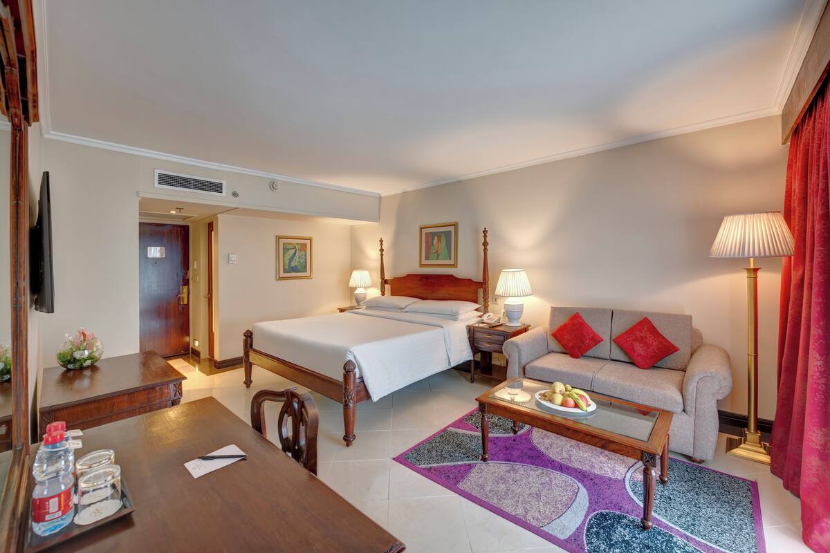Une chambre d’hôtel comprenant un lit, un canapé, une table basse, un bureau et un téléviseur.