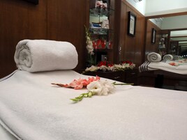 Una cama bien hecha con una toalla blanca enrollada y un arreglo floral sobre la cama.